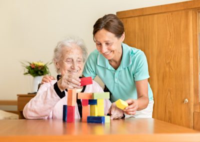 Dementia and Occupational Therapy - Home caregiver and senior adult woman playing with blocks